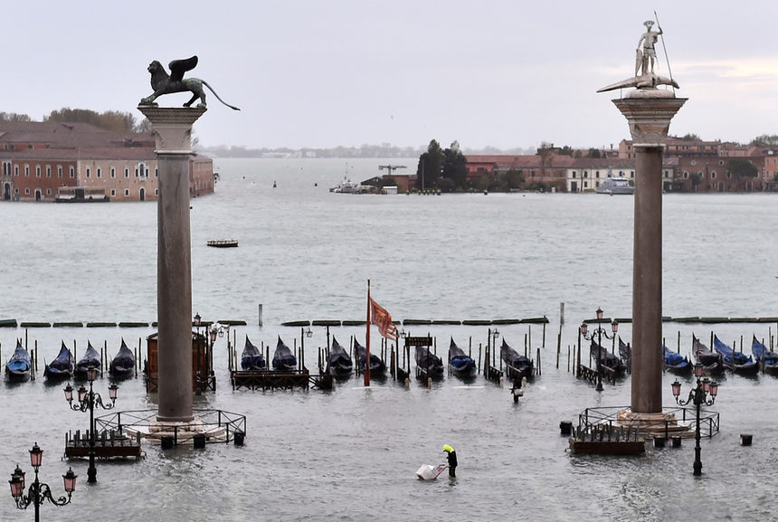 Човек стои на наводнения площад "Сан Марко" във Венеция. Приливът достигна пиково ниво и това принуди италианското правителство да обяви извънредно положение.