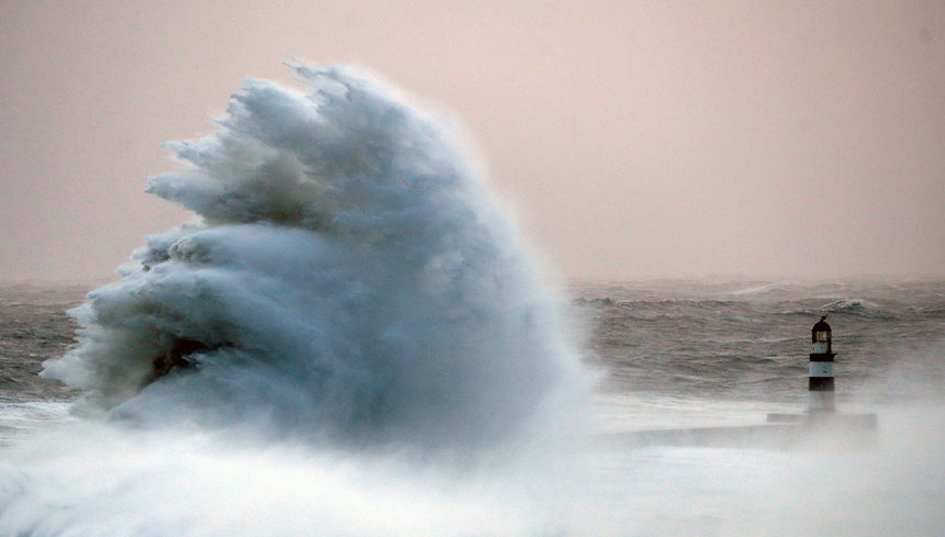 Вълни се разбиват в стената на кея при фара Сийъм по време на бурята "Аруен" в Източна Англия.