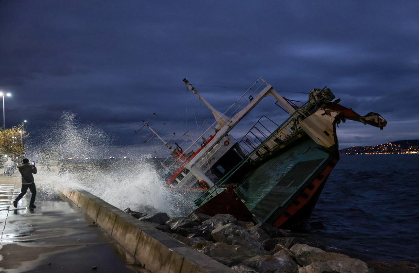 Мъж снима един от корабите, заседнали на брега на Мраморно море, след като силни ветрове ги откъснаха от котвите им, в истанбулския квартал Малтепе, Турция.