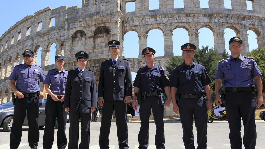 Международна група от полицаи позира пред римски амфитеатър в град Пула. Всеки един от представителите на реда носи различна униформа, характерна за собствената му национална полицейска служба.