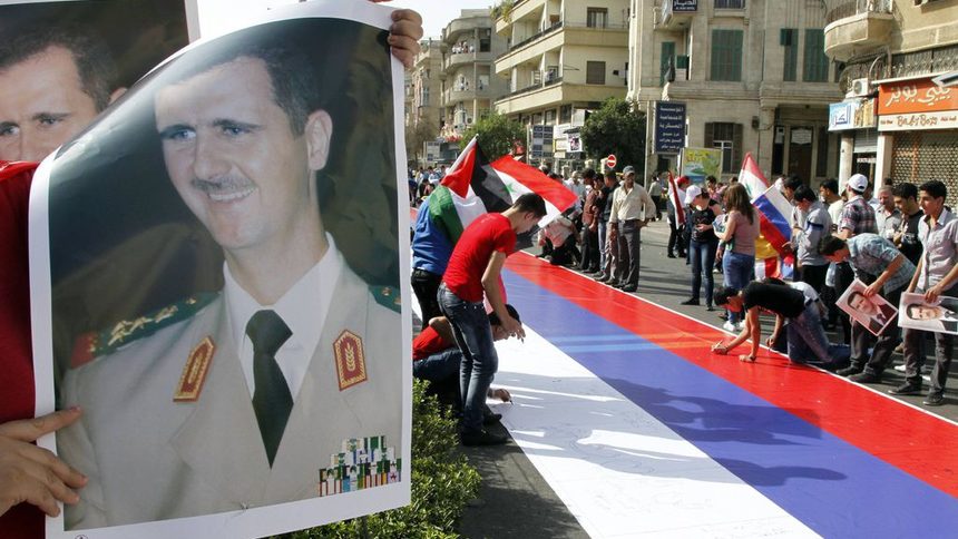 Привърженици на президента Башар ал Асад се подписват върху голямо руско знаме на митинг в Дамаск на 12 октомври 2011 г. Русия и Китай наложиха вето на проекторезолюция на Съвета за сигурност на ООН, осъждаща насилието на режима на Асад.