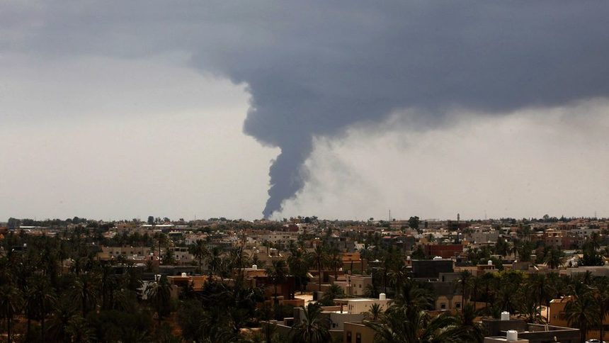 Гъсти талази дим се издигат в небето, след като първата ракета удари цистерна за съхранение на петрол край летището в Триполи
