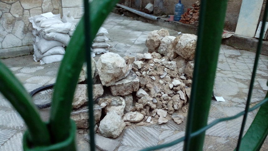 Останките от разрушената порта на къщата са струпани на куп в двора й.