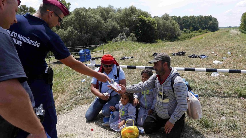 Унгарски гранични полицаи дават вода на сирийци, прекосили границата със Сърбия.