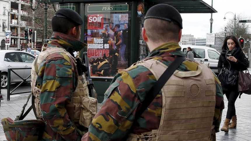 Войници в центъра на Брюксел до павилион с реклама на местно списание с водещо заглавие "Във война сме".