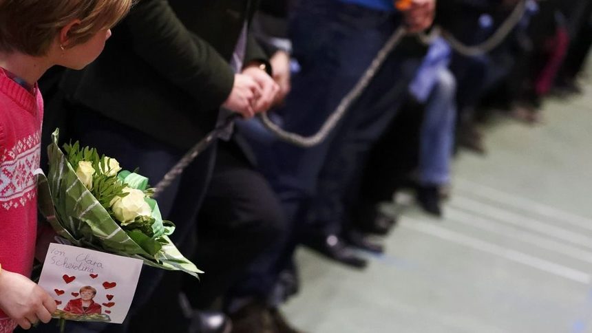 Момиченце държи картичка и цветя в очакване да ги даде на канцлера Ангела Меркел.