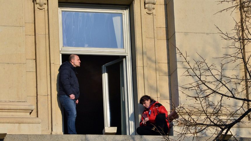 Бойка Анастасова излезе на перваза на втория етаж на сградата на Партийния дом, а служител на НСО опитва да я убеди да влезе вътре.
